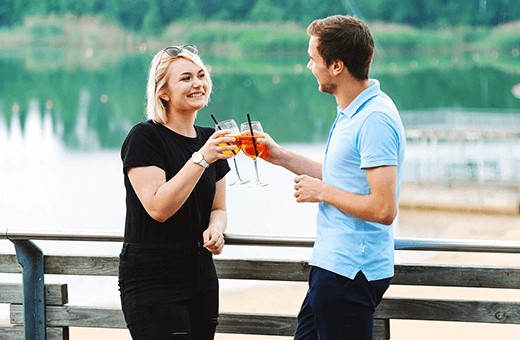 Zwei Menschen prosten sich auf der Seeterrasse zu