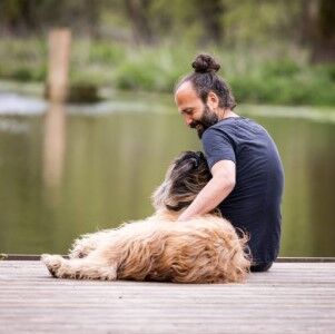 Hundetrainer sitzt mit Hund am See